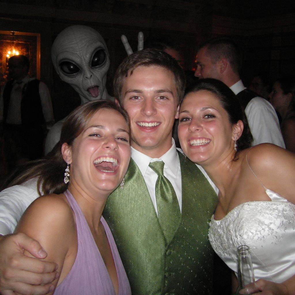 Friends posing at a party with an alien photobombing the group